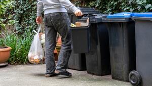 Mann bringt seinen Müll zu Mülltonnen