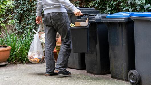 Mann bringt seinen Müll zu Mülltonnen