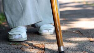 Eine Frau steht mit einem Stock auf einem Gehweg