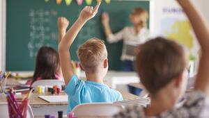 Kinder in einer Grundschulklasse, die sich melden, von hinten zu sehen