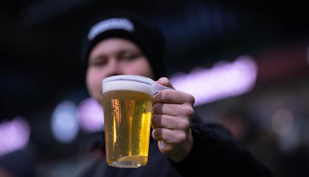 Fan hält Bier im Stadion