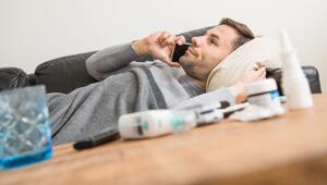 Ein Mann liegt krank auf einem Sofa und telefoniert