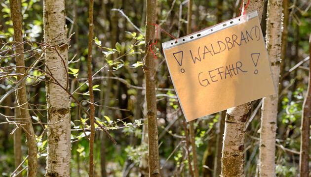 Handgeschriebener Zettel, der vor Waldbrandgefahr warnt