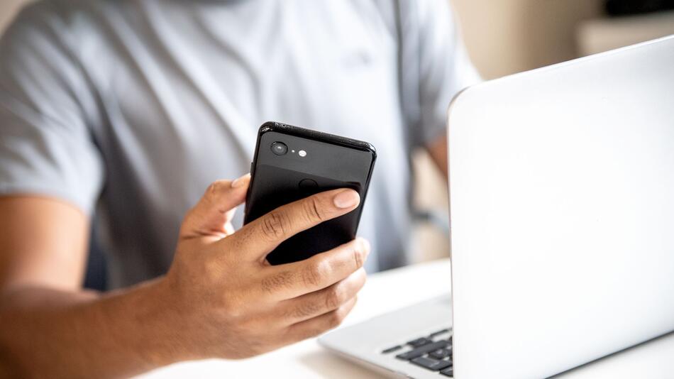 Mann mit Smartphone und Laptop