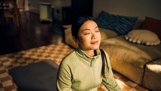 Junge Frau beim Meditieren im Wohnzimmer. 