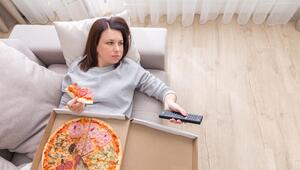 Frau liegt mit Pizza auf der Couch