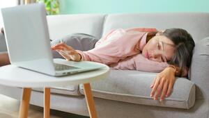 Frau liegt am Sofa und müsste eigentlich arbeiten