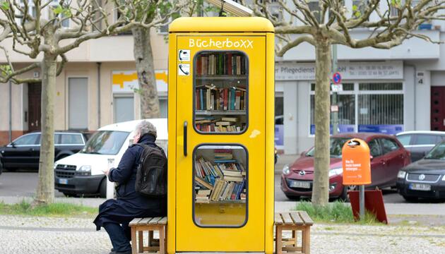 Ein Mann liest vor einer BücherboXX in Charlottenburg-Nord in Berlin ein Buch