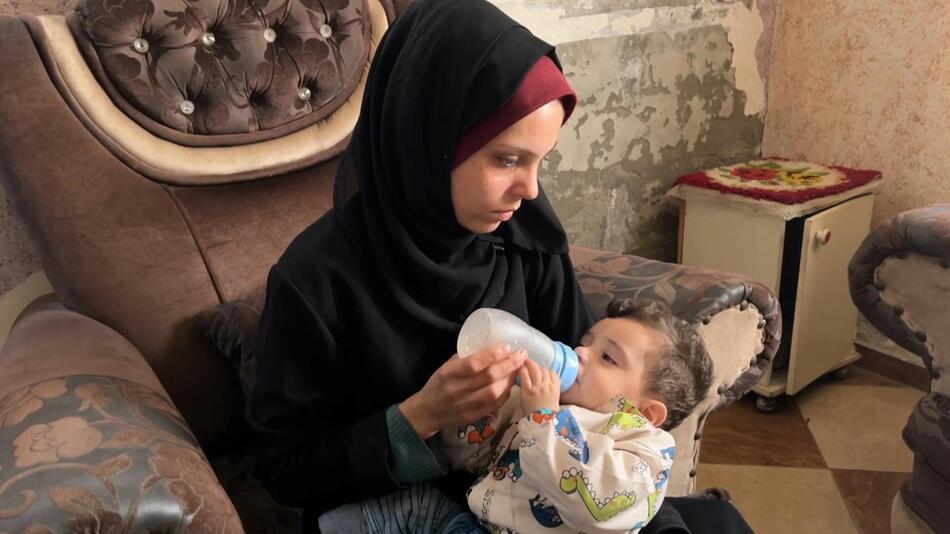Eine Frau im Gazastreifen gibt ihrem kleinen Sohn die Milchflasche