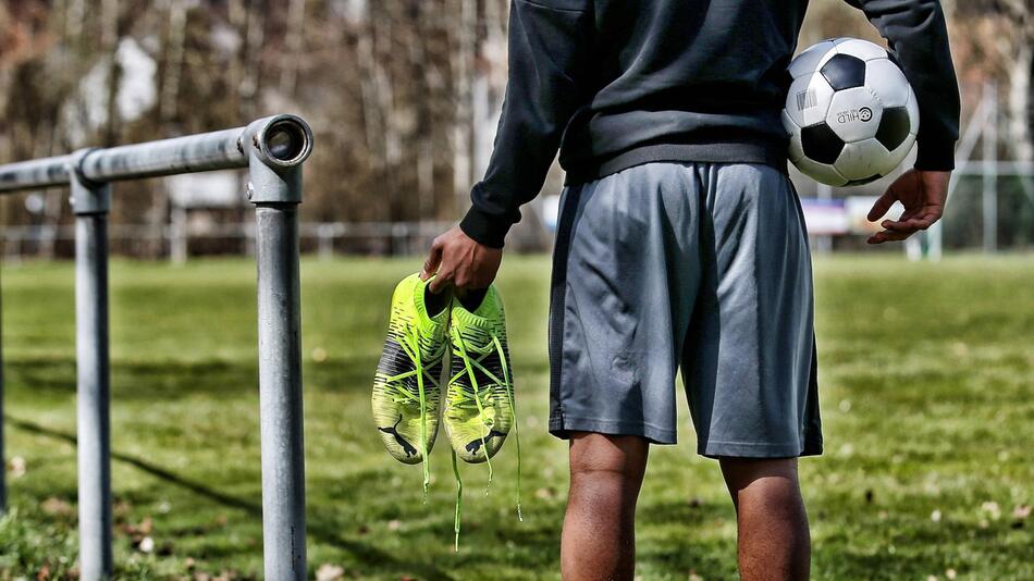 Junge mit Ball und Fußballschuhen