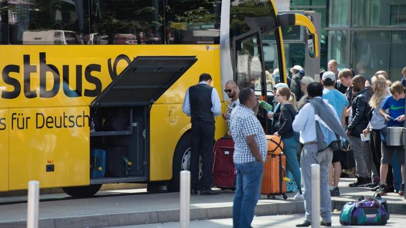 Reisende an Postbus-Haltestelle