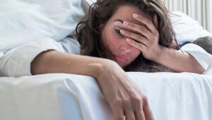 Frau fässt sich verschlafen an den Kopf