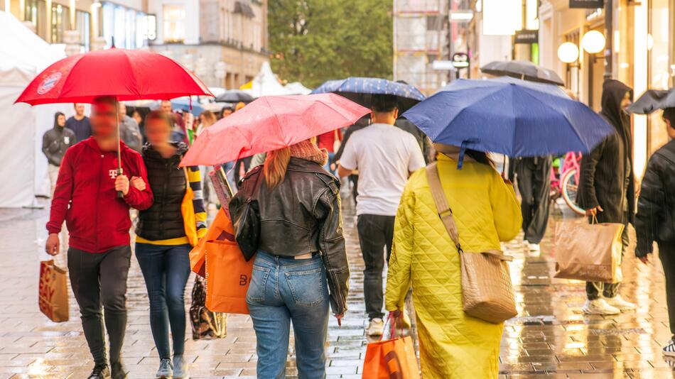 Passanten mit Regenschirmen in einer Fußgängerzone