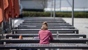 Eine Studentin sitzt auf den Bänken einer Mensa