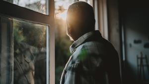 Älterer Mann sieht aus dem Fenster
