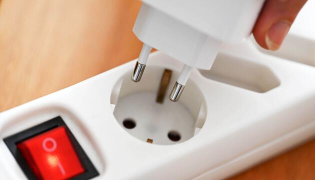 Eine Steckerleiste mit Steckdosen für Strom liegt in einem Privathaushalt auf einem Tisch.