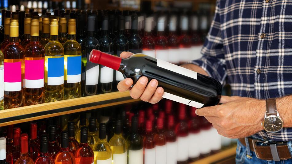 Mann hält Flasche Wein in der Hand