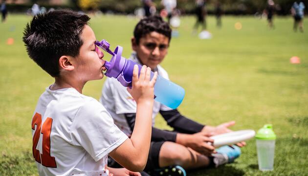 Junge trinkt Wasser am Sportplatz