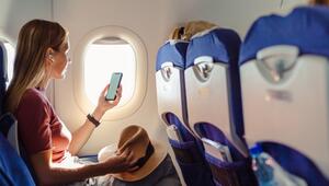 Eine Frau benutzt in einem Flugzeug ihr Smartphone.