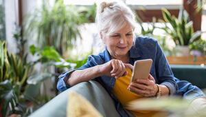 Seniorin ist am Handy und lächelt