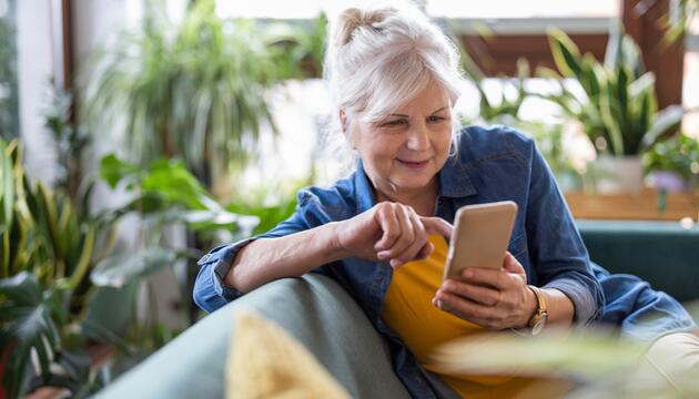 Seniorin ist am Handy und lächelt