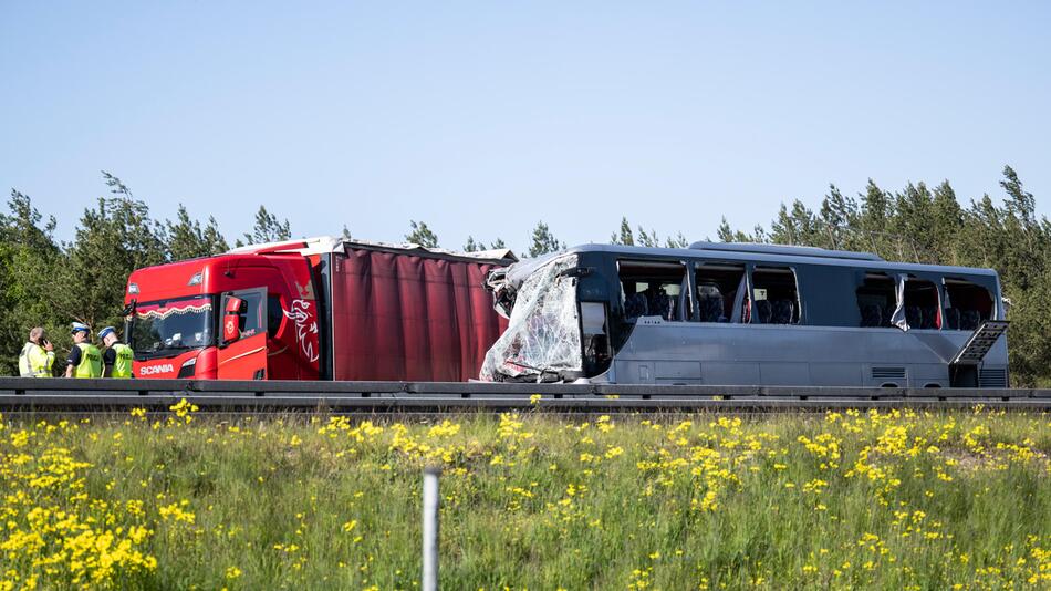 Ein Lkw und ein zerstörter Bus stehen auf der Autobahn.