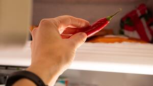 Eine Frau legt eine Chili in ein Eisfach