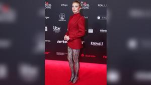 Helena Zengel in ihrem roten Komplett-Look mit schwarzer Spitzenstrumpfhose.