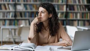 Junge Frau sitzt nachdenklich vor ihrem Laptop, sie wirkt besorgt