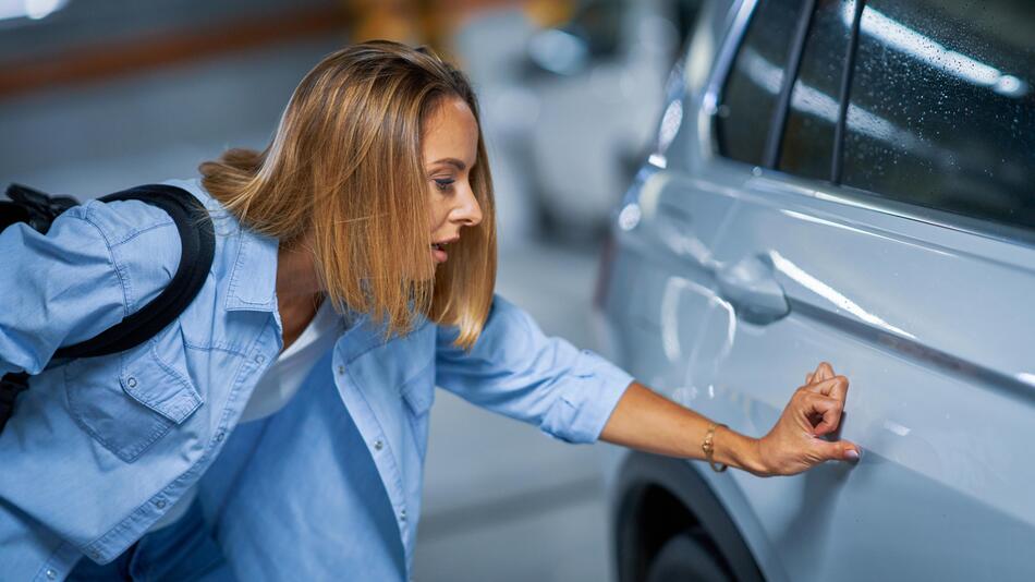 Porträt einer jungen Frau mit zerkratzten Auto auf Tiefgarage