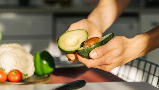 Zwei Hände halten eine aufgeschnittene Avocado.