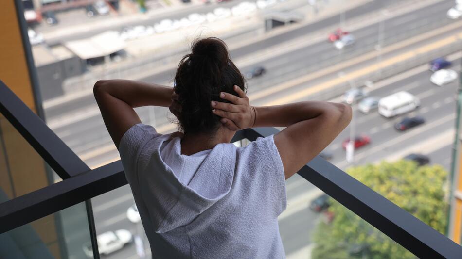 Frau steht auf Balkon über Straße