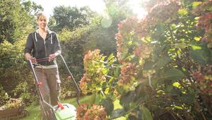 Eine Frau mäht den Rasen in einem Garten