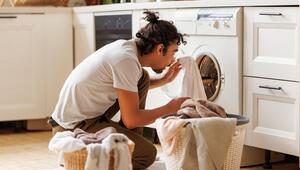 Junger Mann, der auf dem Boden sitzt und Wäsche macht.