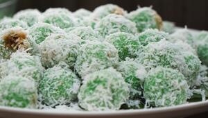 Indonesische Klepon werden mit Kokosraspeln bestreut und auf Bananenblättern serviert.