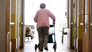 Eine Frau geht mit einem Rollator in einem Altenheim