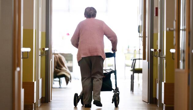 Eine Frau geht mit einem Rollator in einem Altenheim