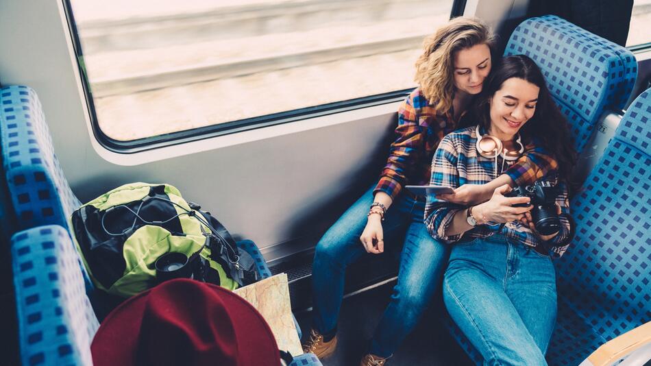 Junge Frauen fahren mit dem Zug, sie haben Gepäck dabei