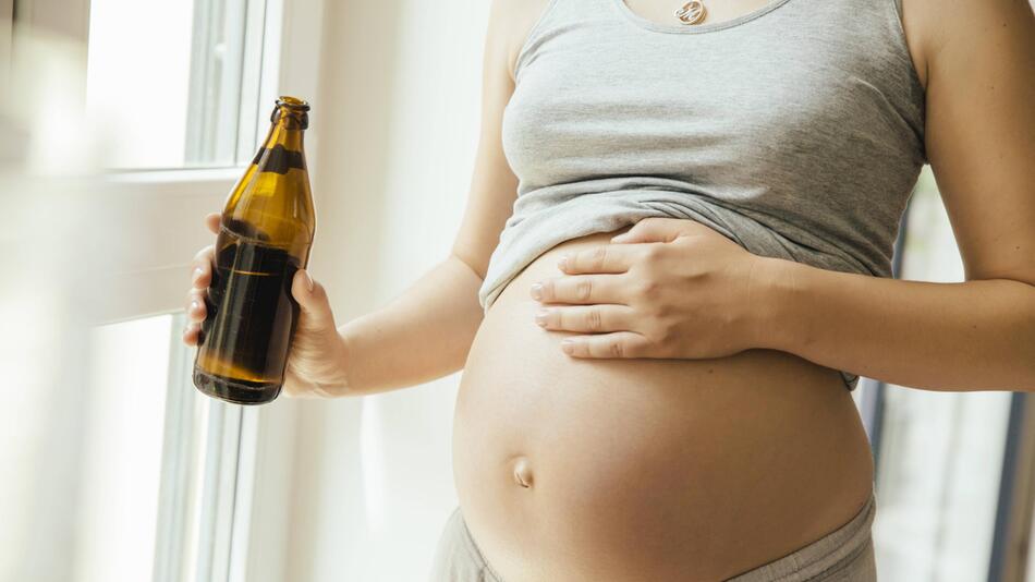 Schwangere Frau mit Bierflasche