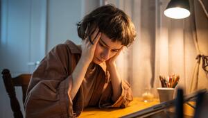 Frau mit Händen am Kopf an Schreibtisch