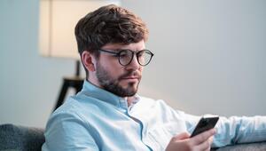 Junger Mann, der auf sein Handy schaut. 