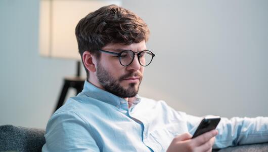 Junger Mann, der auf sein Handy schaut. 