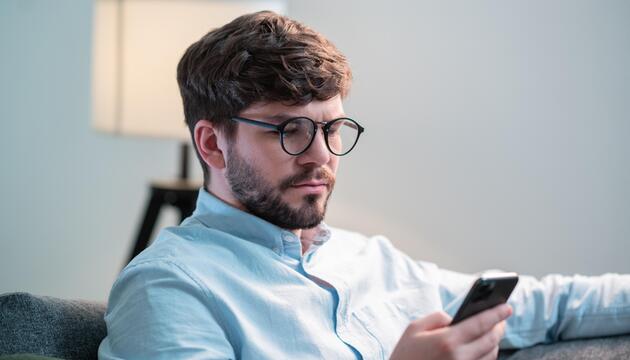 Junger Mann, der auf sein Handy schaut. 