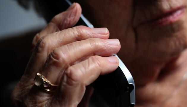 Seniorin telefoniert mit einem Festnetztelefon