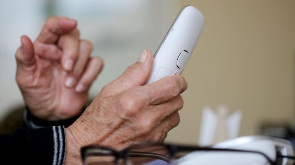 Rentner hält Telefon in der Hand