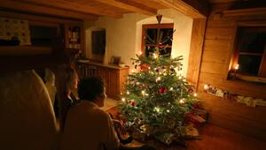 Familie sitzt vor einem beleuchteten Weihnachtsbaum