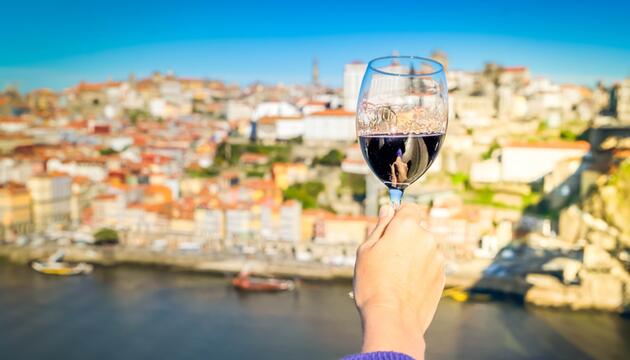 Person trinkt am Fluss Douro ein Glas Wein