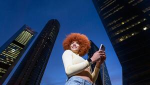 Eine Frau mit einem roten Afro steht vor Hochhäusern.
