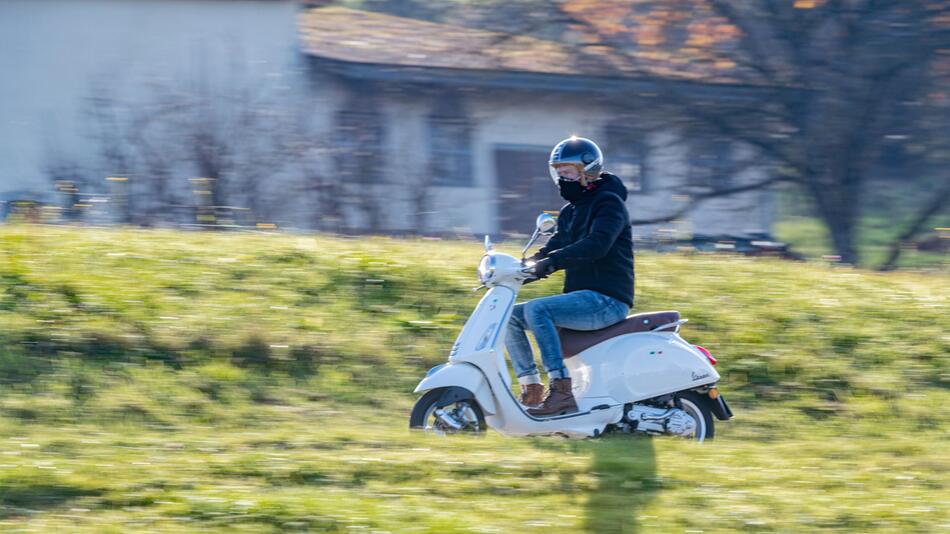 Mann fährt mit einem Motorroller