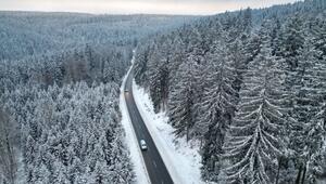 Autos fahren auf Landstraße durch den Winterwald im Vogtland